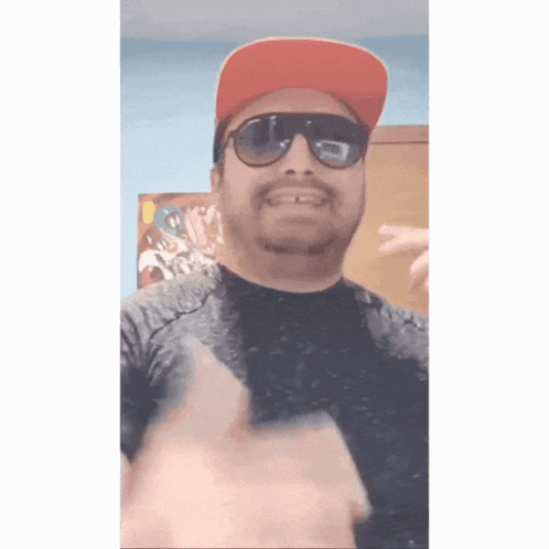 a man wearing a red hat and sunglasses is giving a thumbs up