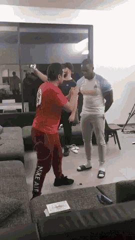 a man in a red nike air shirt is standing in a living room