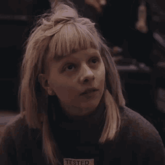 a woman with blonde hair is wearing a sweater that says " tested " on it