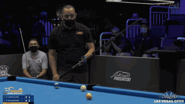 a man is playing pool in front of a wall that says predator