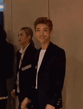 a man in a black jacket with the word jeongh on it is waving