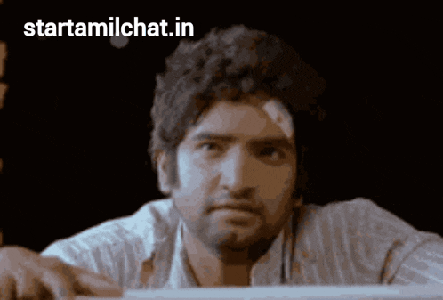 a man with a beard is sitting at a table and the website starttamilchat.in is visible behind him
