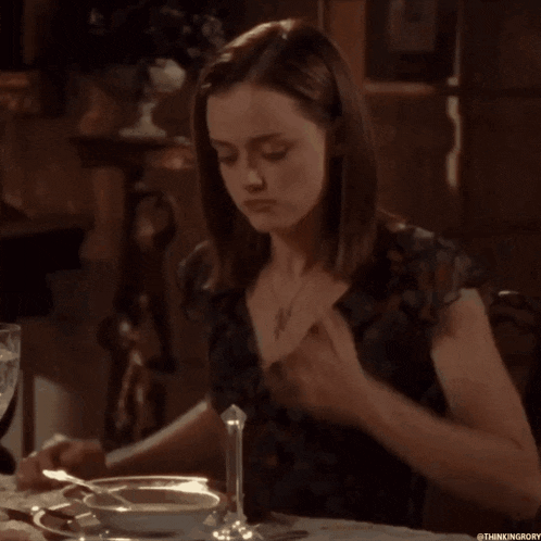 a woman is sitting at a table with a bowl of soup and a candle