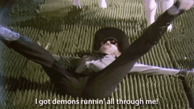 a man in a cowboy hat is laying on the ground with the words i got demons runnin ' all through me below him