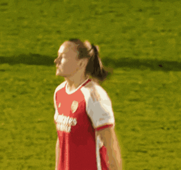 a soccer player wearing a red emirates fly better jersey stands on the field .