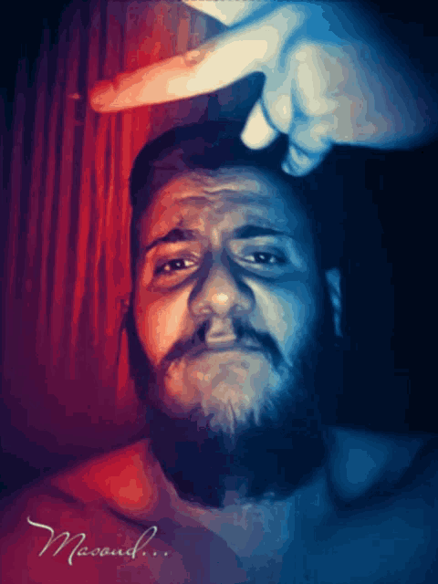 a man with a beard is being touched by someone 's finger and the name masoud is on the bottom of the picture