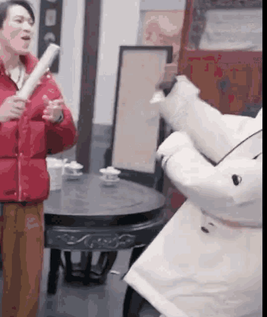 a man in a red jacket is standing next to a woman in a white coat holding a sword .
