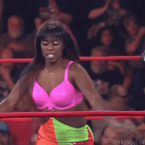 a female wrestler is laying on the ground in a wrestling ring while a cameraman takes a picture