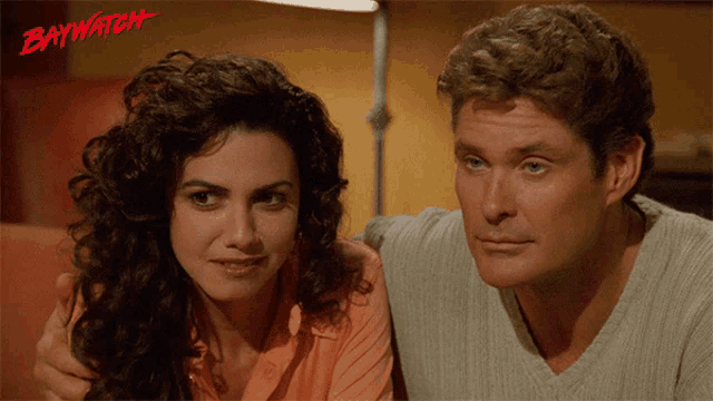 a man and a woman are sitting next to each other with the word baywatch on the bottom