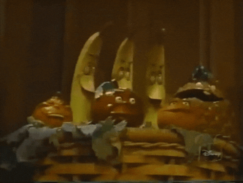 a bunch of bananas and oranges in a basket with a disney logo in the corner