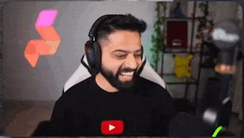 a man with a beard wearing headphones is sitting in front of a microphone and smiling .