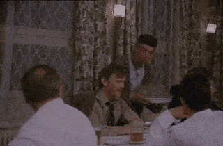 a group of men are sitting at a table in a restaurant while a waiter serves food .