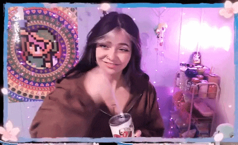 a girl is drinking from a can with a straw in front of a pixel art of link