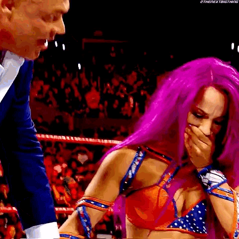 a woman with purple hair is covering her mouth while a man in a suit stands next to her .