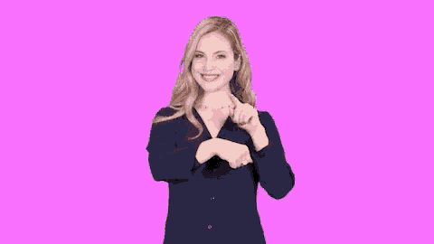 a woman wearing a blue shirt is making a heart shape with her hands .
