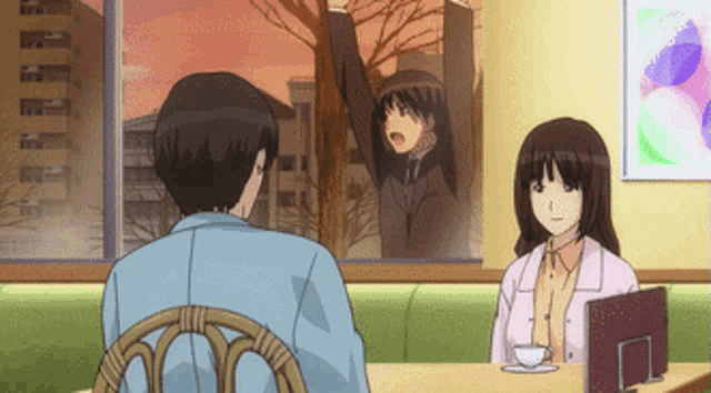 a man and woman sit at a table with a cup of coffee