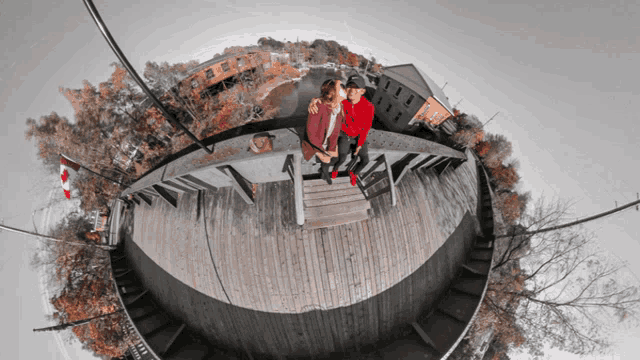 a couple sitting on a wooden deck with a canadian flag behind them