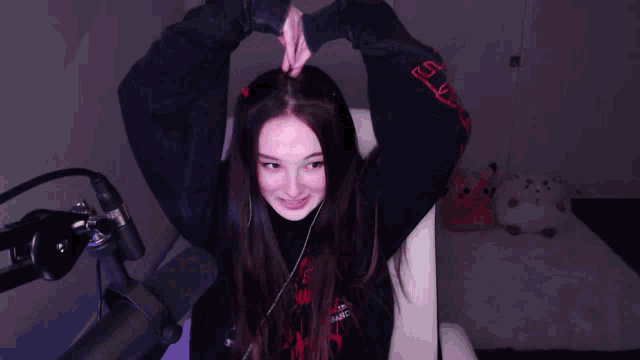 a girl sitting in front of a microphone with her hands in the air