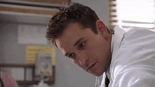 a close up of a man in a lab coat looking down .