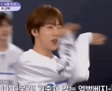 a young man in a white shirt is dancing on a stage with his arms outstretched .
