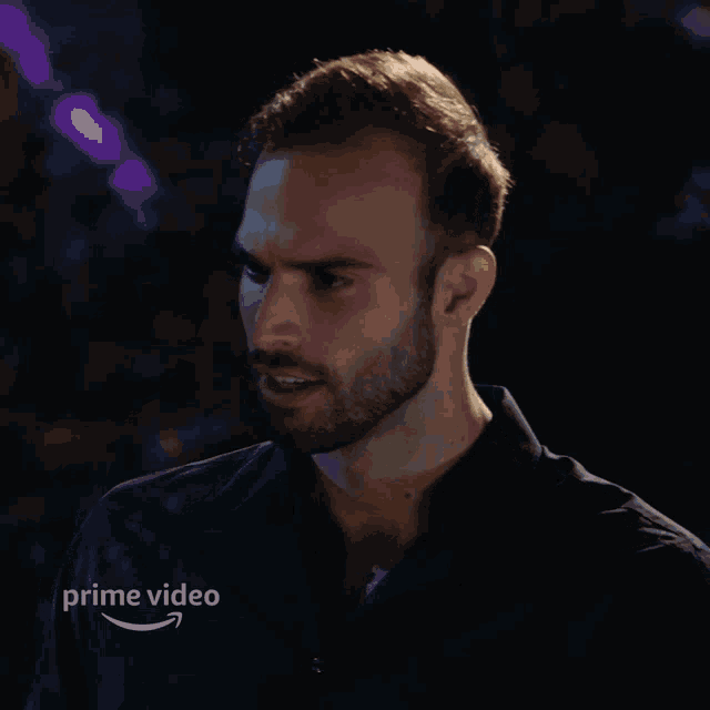 a man with a beard is standing in the dark with a prime video logo