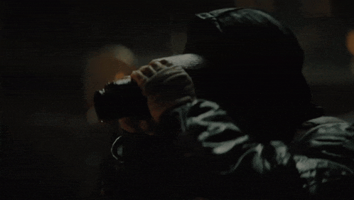 a person looking through binoculars with a hat on
