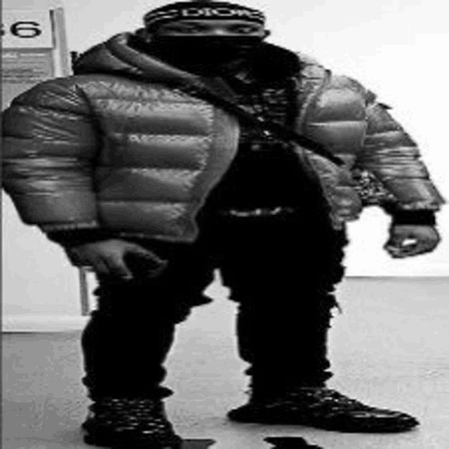 a black and white photo of a man wearing a puffer jacket and a hat .