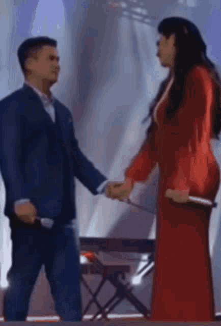 a man in a suit and a woman in a red dress holding hands