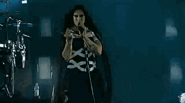 a woman with long hair is singing into a microphone on a stage