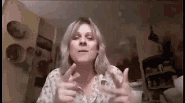a woman is giving a thumbs up sign while sitting in front of a computer screen .