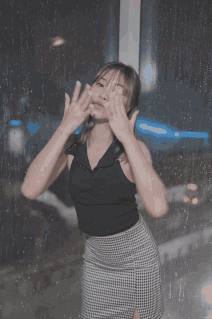 a woman stands in front of a window with her hands up in the air