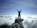 a man is standing on top of a mountain with his arms outstretched .