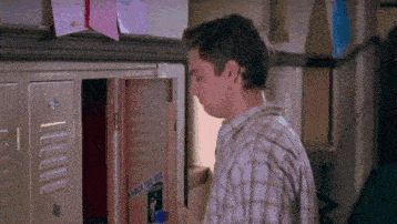 a man in a plaid shirt is looking into a locker .
