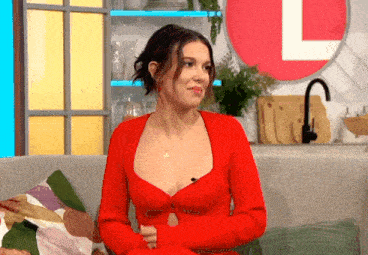 a woman in a red dress is sitting on a couch in front of a large letter l