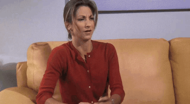a woman in a red sweater is sitting on a couch