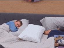 a person is sleeping on a bed with a blanket and pillows