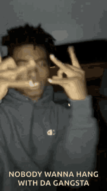 a man is making a peace sign with his hands while wearing a champion hoodie .