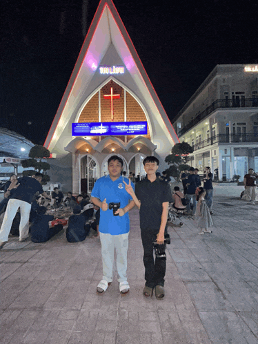 two young men standing in front of a church with a sign that says tri lieu on it