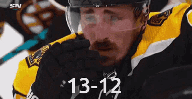 a hockey player is wearing a helmet and gloves and the number 13-12 is on the screen