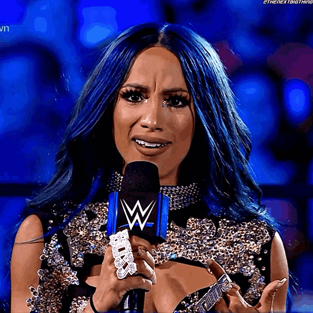 a woman with blue hair is holding a microphone that says wwe