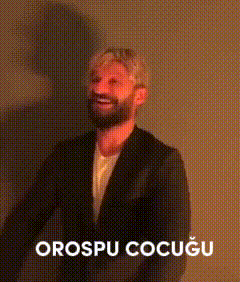 a man with a beard wearing a suit and a white shirt is smiling with the words orospu cocugu below him .
