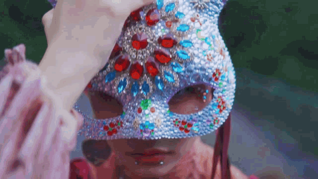 a woman wearing a colorful mask with rhinestones