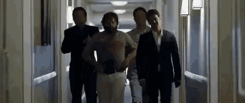 a group of men are walking down a hallway in a hotel room .