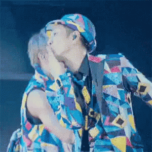 two men are kissing each other on the cheek while wearing colorful clothes .