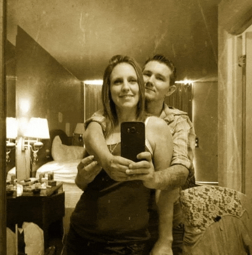 a man and a woman are taking a selfie in a hotel room