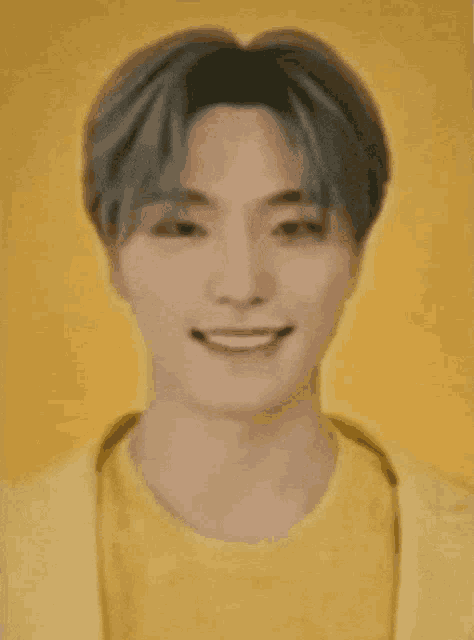 a young man wearing a yellow shirt and a yellow jacket is smiling against a yellow background .
