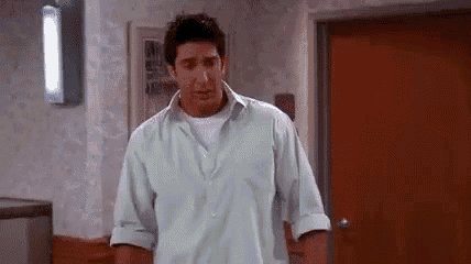 a man in a light blue shirt is standing in a hallway .