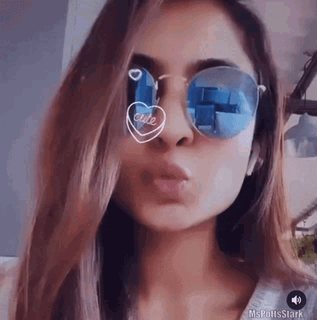 a woman wearing sunglasses is blowing a kiss and making a face .