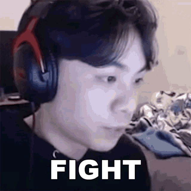 a man wearing headphones is sitting in front of a computer screen and says `` fight '' .