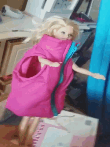 a barbie doll is wrapped in a pink blanket with a blue ribbon